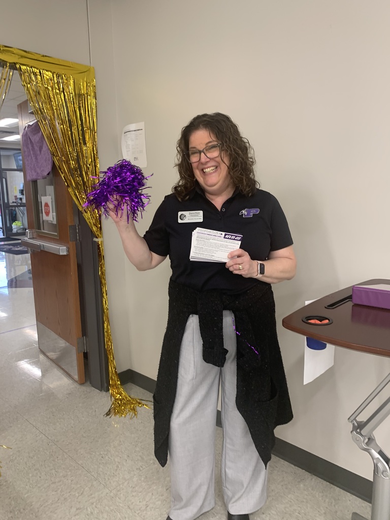 Staff member holding a purple pom pom while smiling.