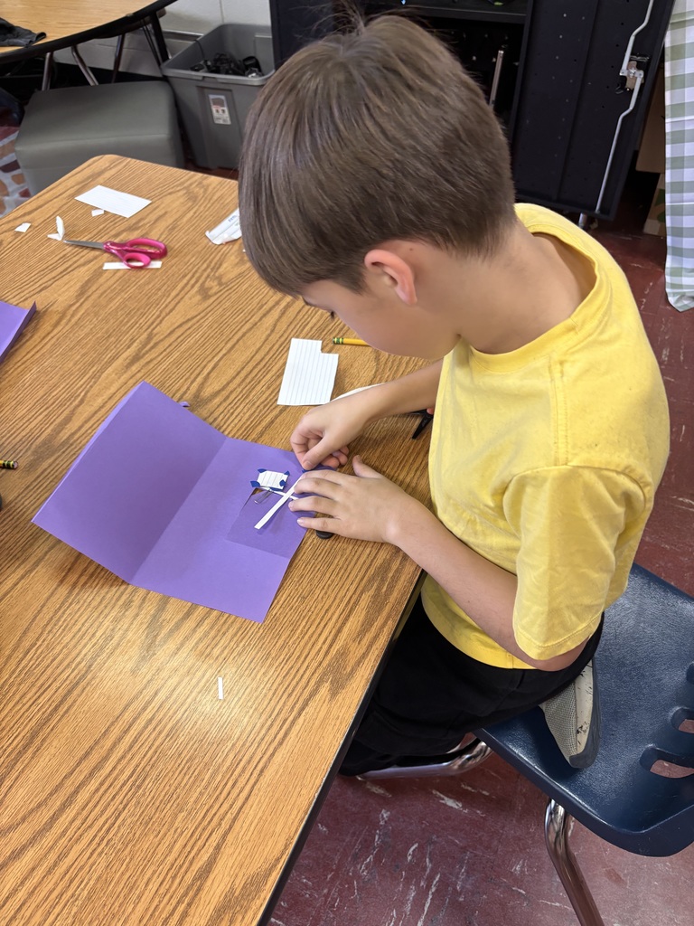 Student working on an assignment in a classroom with purple paper.