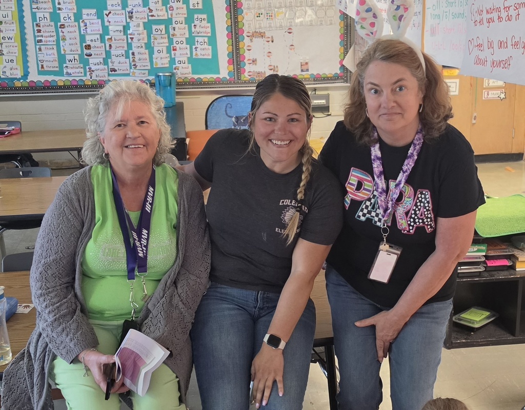 Three staff members smiling for a group photo in a classroom. 