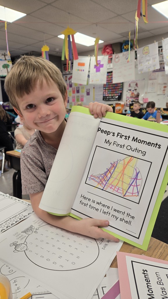 Young student showing a drawing on a piece of paper labeled "Peep's first moments."