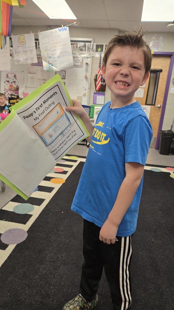 Young student showing a drawing on a piece of paper labeled "Peep's first moments."