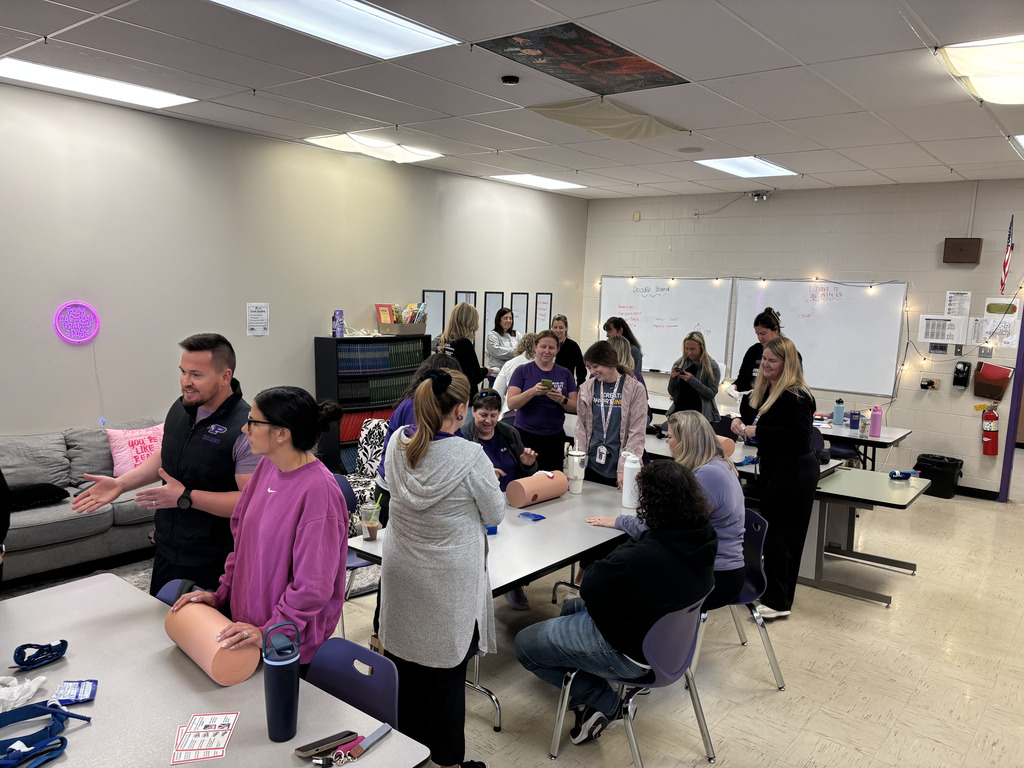 Various staff members participating in an activity in a classroom at desks.