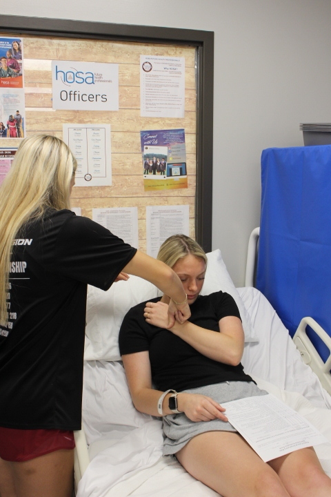 Two students doing coursework in a fake hospital bed.
