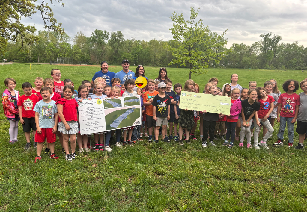 A group of students outside holding a large banner and a large fake check.