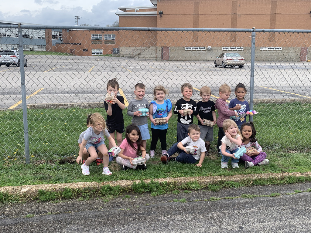 Group of students holding colored eggs while posing for a photo outside.