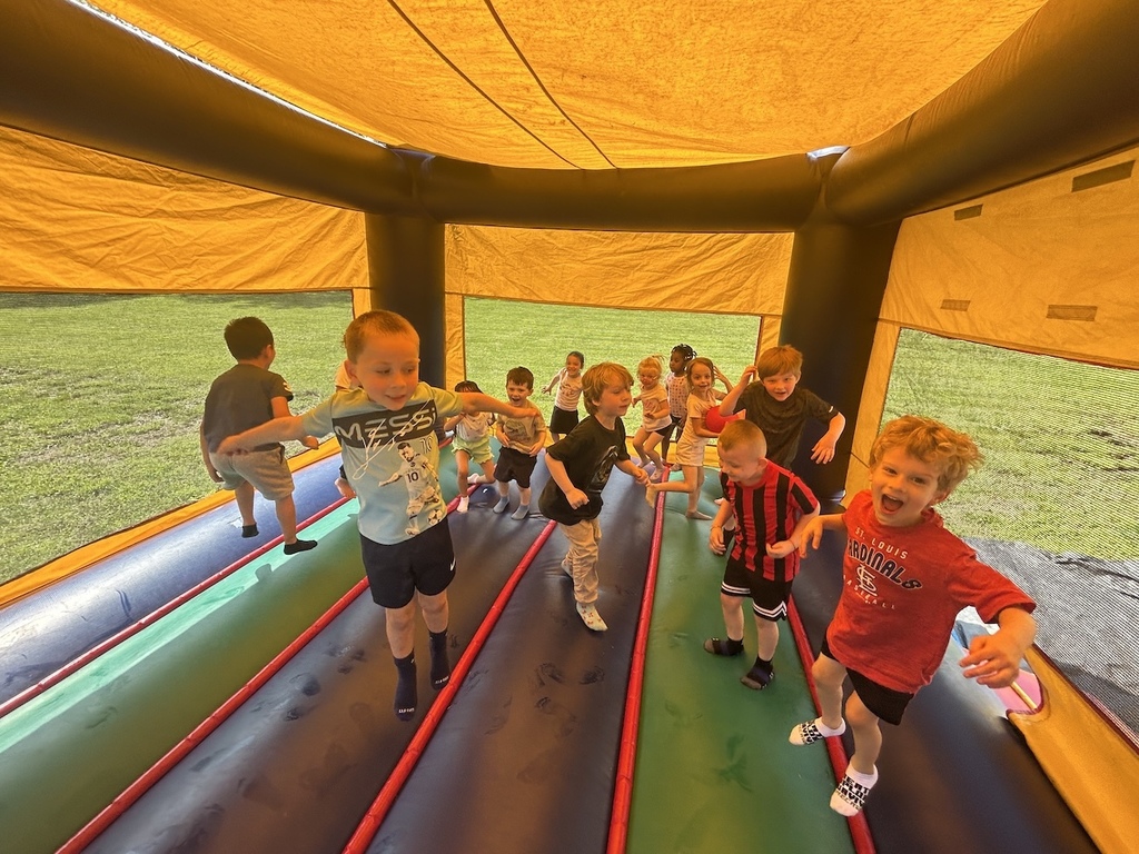 Young students jumping in a colorful bouncy house.