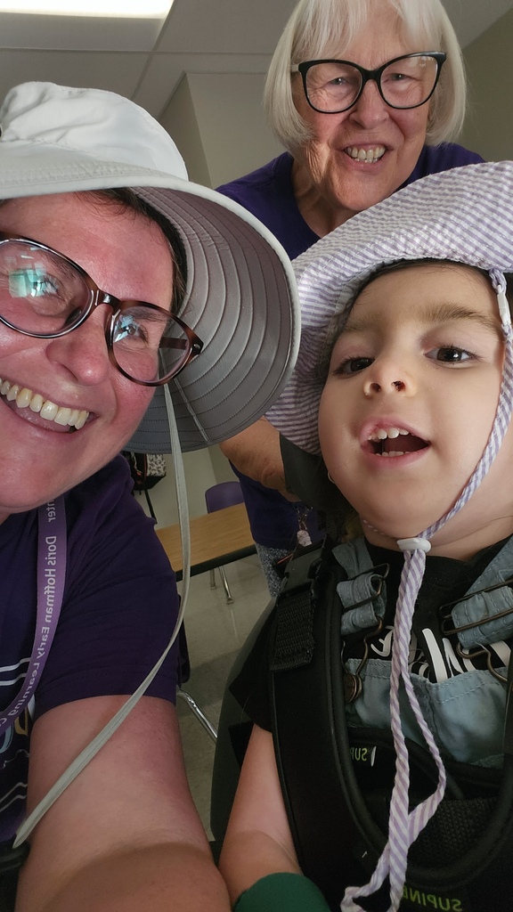 Two adults pose for a selfie with a young student.