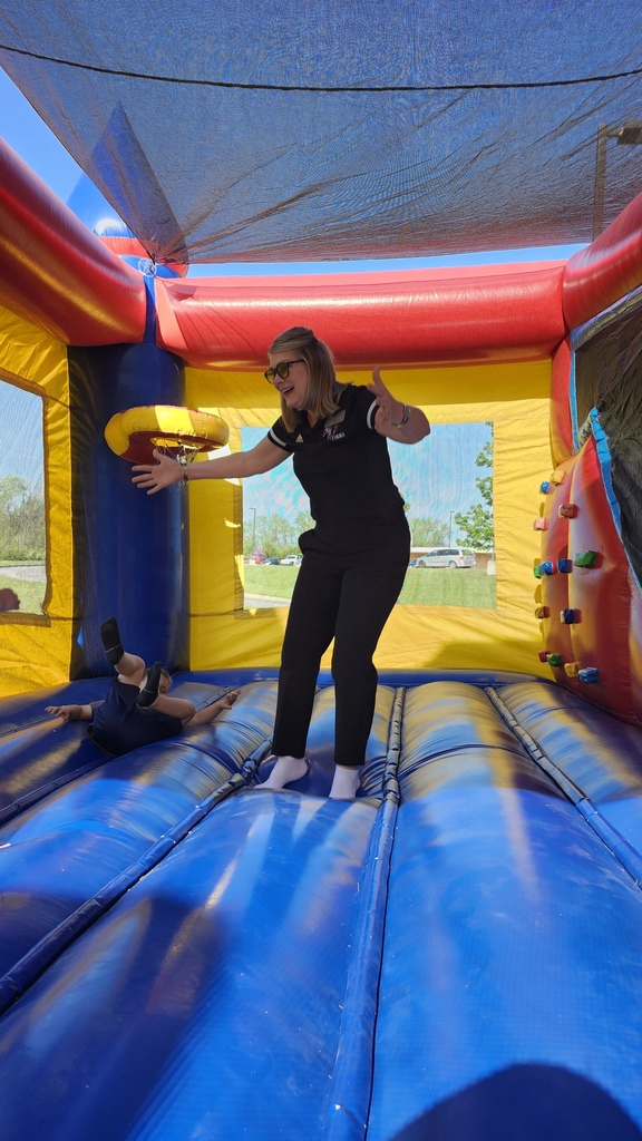 Teacher jumping in a colorful bouncy house with a student.