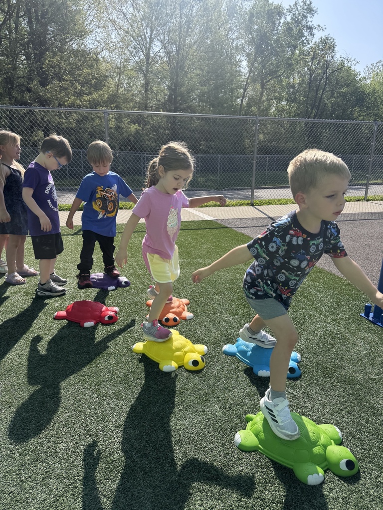 Young students outdoors, stepping onto colorful turtle-shaped steps.