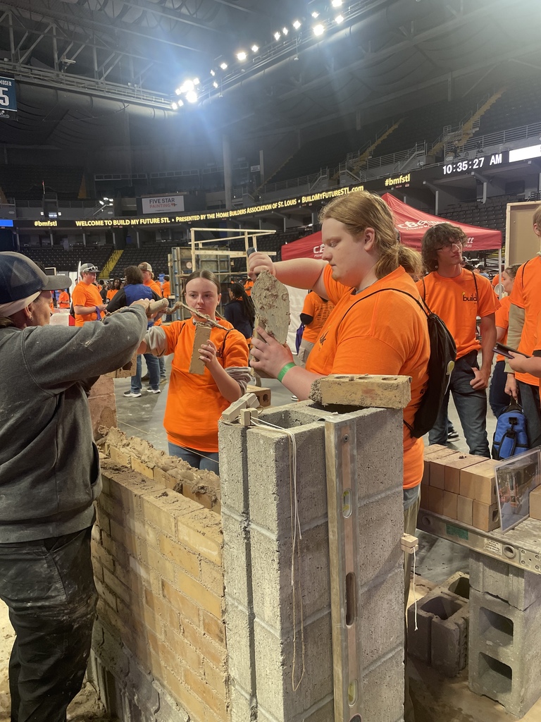 Students building a structure using wood and cement blocks.