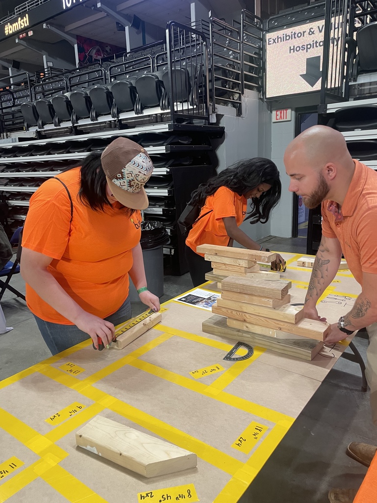 Students measure pieces of wood on a table.