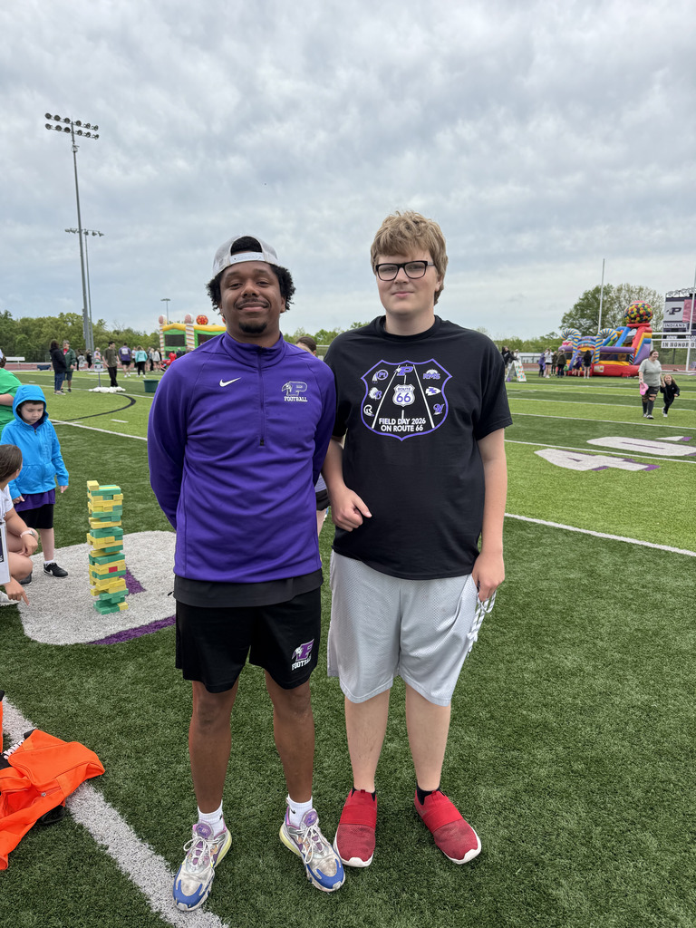 Two students posing for a photo on a football field.
