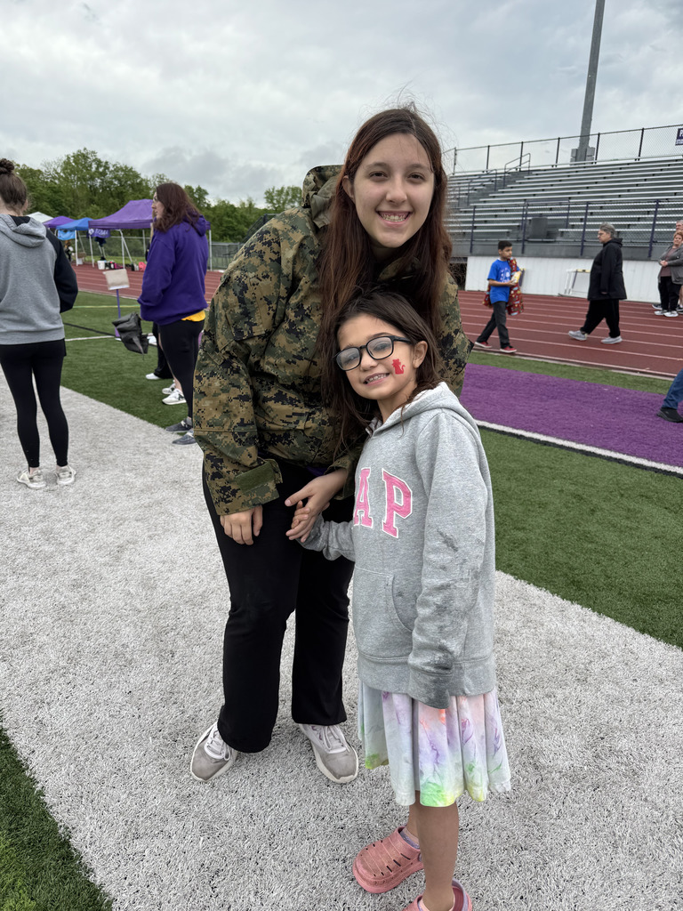 Two students posing for a photo on a purple track and field. 