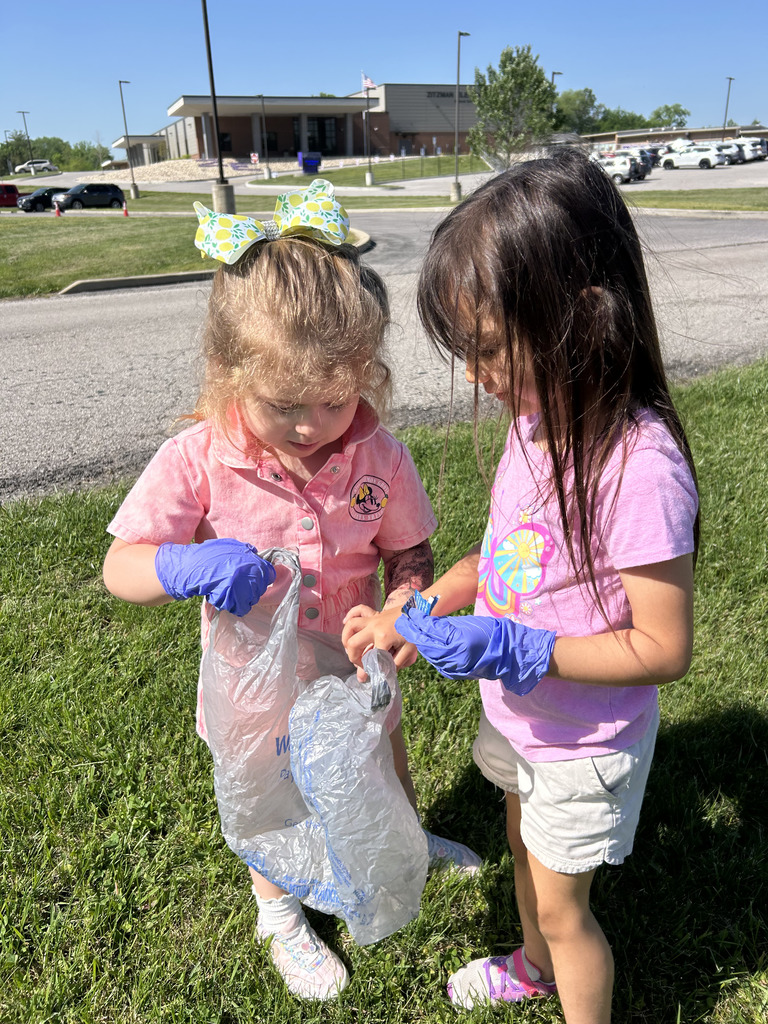 Two students wearing blue gloves and a grocery sack outside.