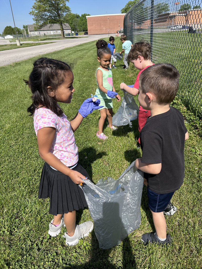 Six students wearing blue gloves and a grocery sack outside.