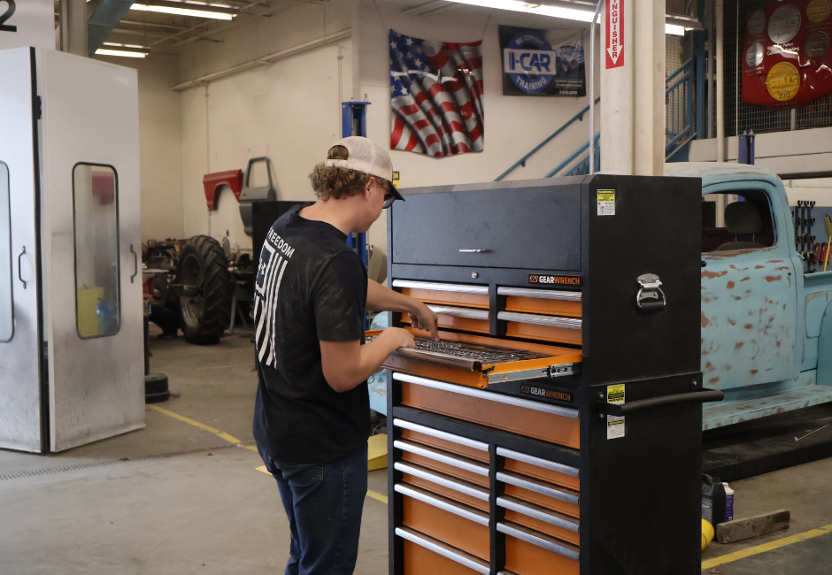 Student gathering tools from a large black and orange toolbox.