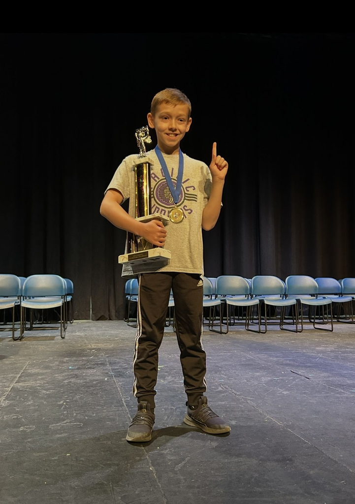 Student standing with a large trophy in hand and holding up a finder as "number one."