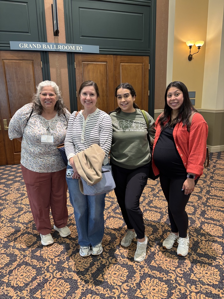 Four staff members pose for a photo in a ballroom.