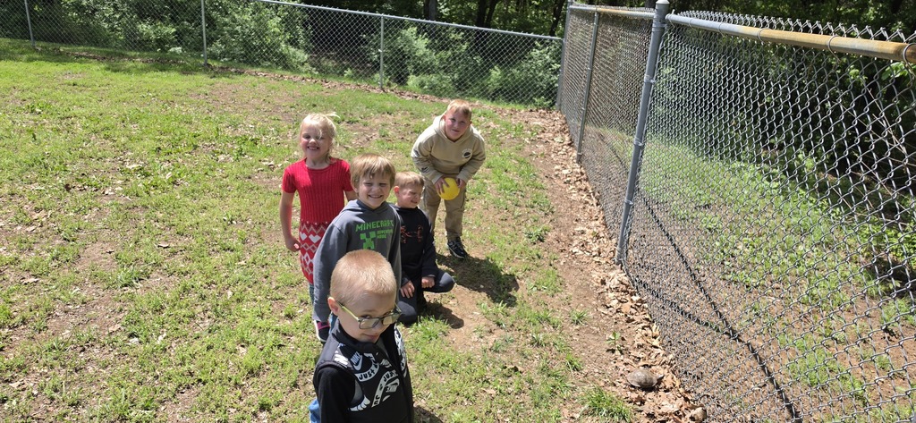 Five students playing outside on green grass.