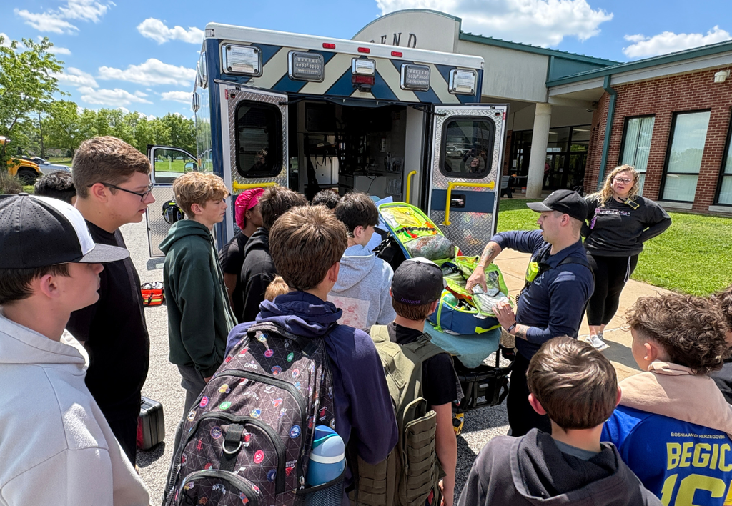 Students gathered around an ambulance learning from a paramedic.