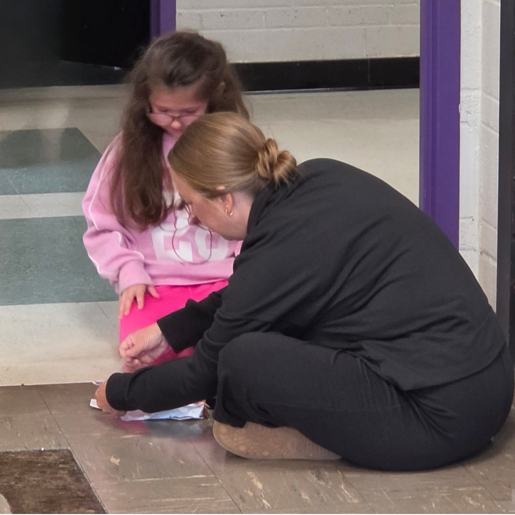 Staff member interacting with a student in the school hallway.