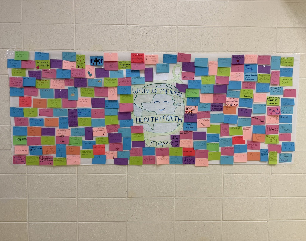 Wall display for World Mental Health Month covered with colorful sticky notes sharing supportive and uplifting messages.