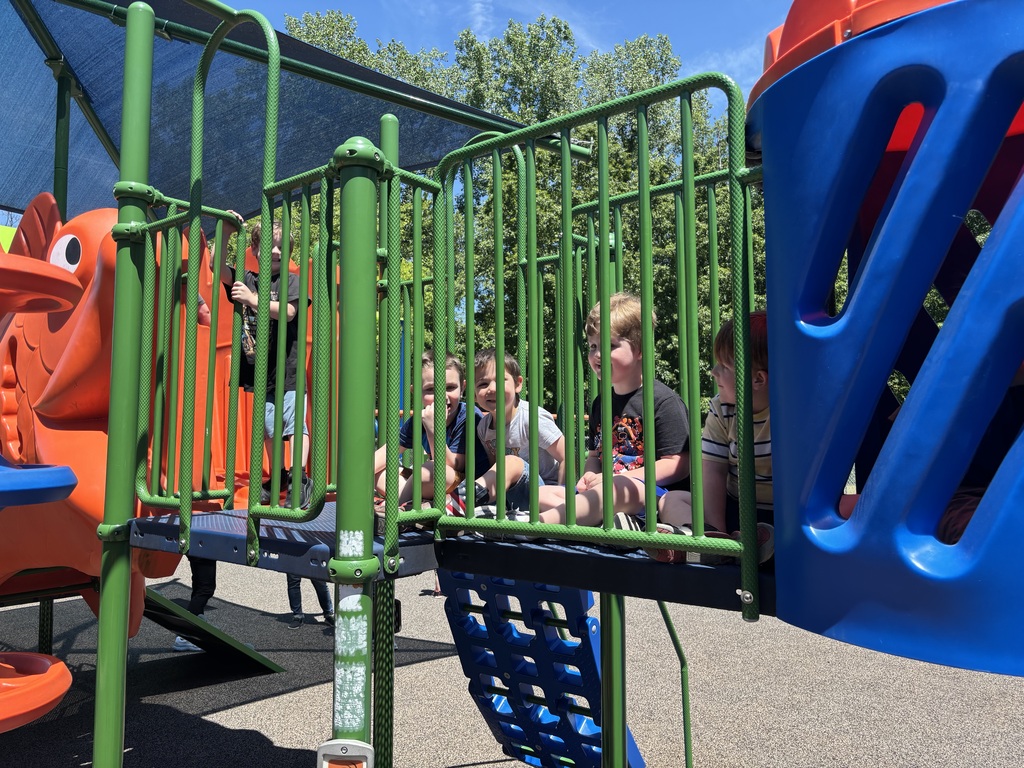 Students smiling on a green playground.