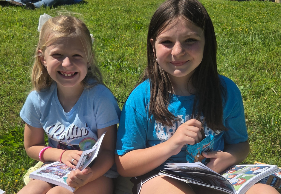 Two students reading outside smiling for a photo.