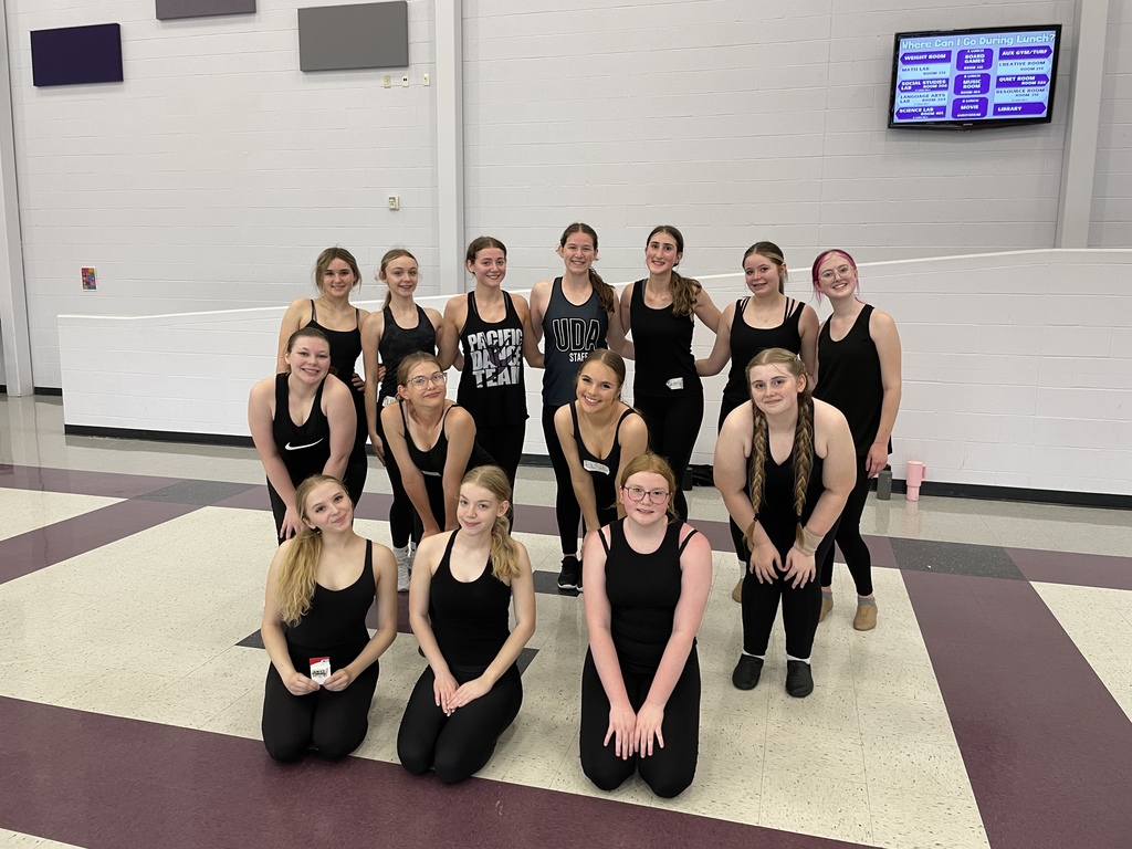 A group of students wearing all black posing in a school gym.