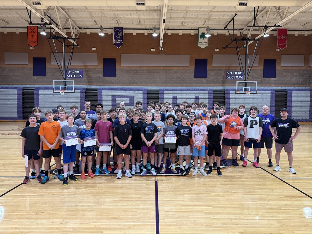 Large group of boys and coaches pose on a gym floor at a summer basketball camp, with award recipients holding certificates in front.