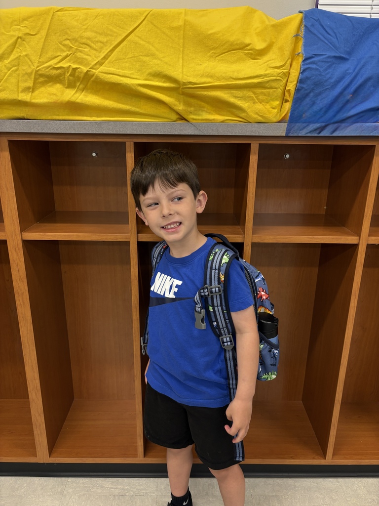 A young students smiles for a photo in a school classroom.