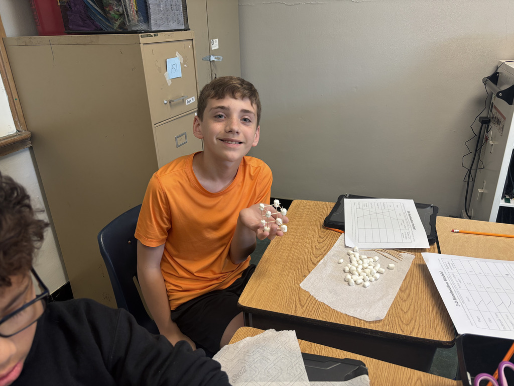 Student holding a 3D model with toothpicks and marshmallows.