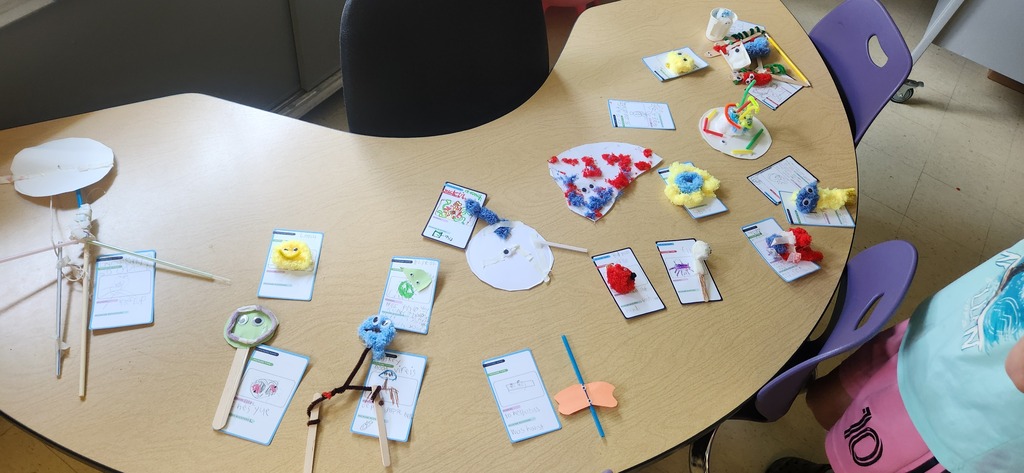 Various student artwork laying on a school desk.