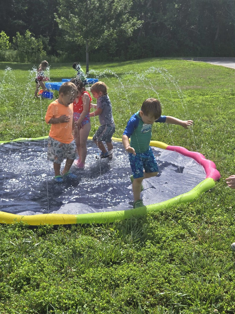 Young students playing in water outdoors.