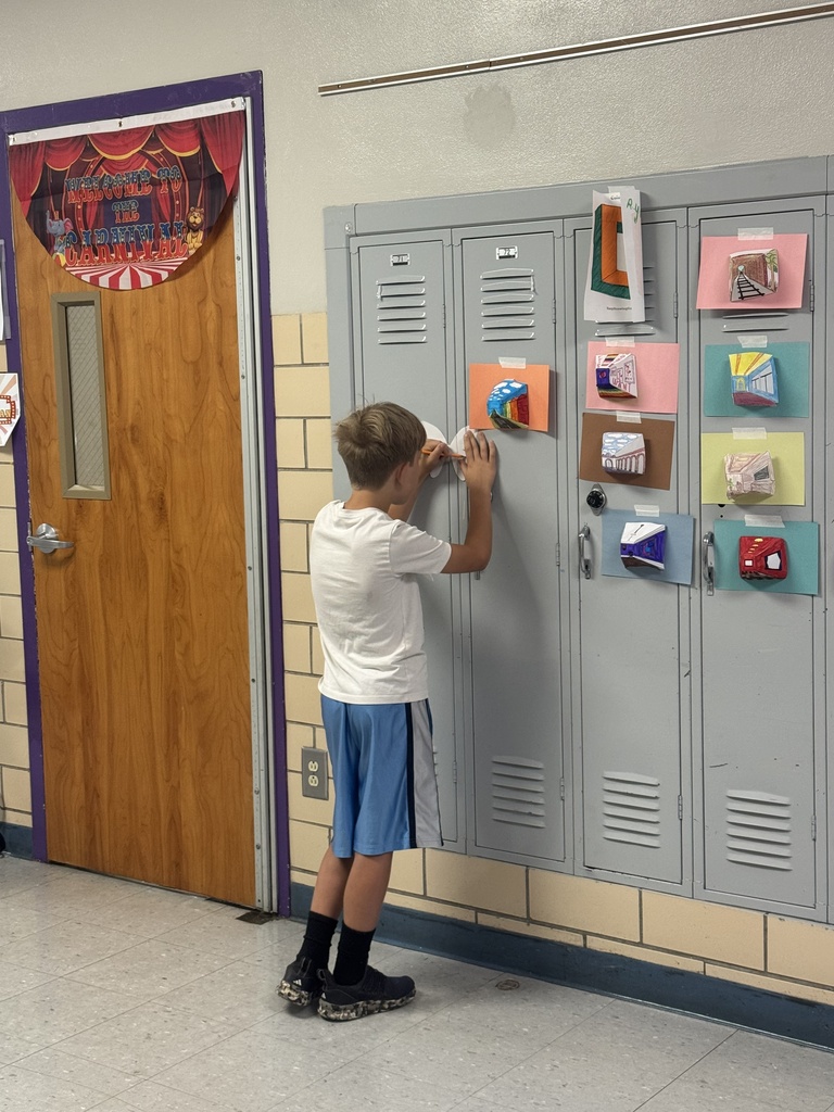 Student displays artwork on hallway lockers as part of a school art showcase.