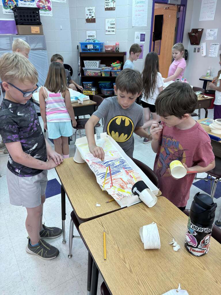 Students collaborate around a homemade marble run, testing and adjusting their design during a hands-on STEM engineering activity.