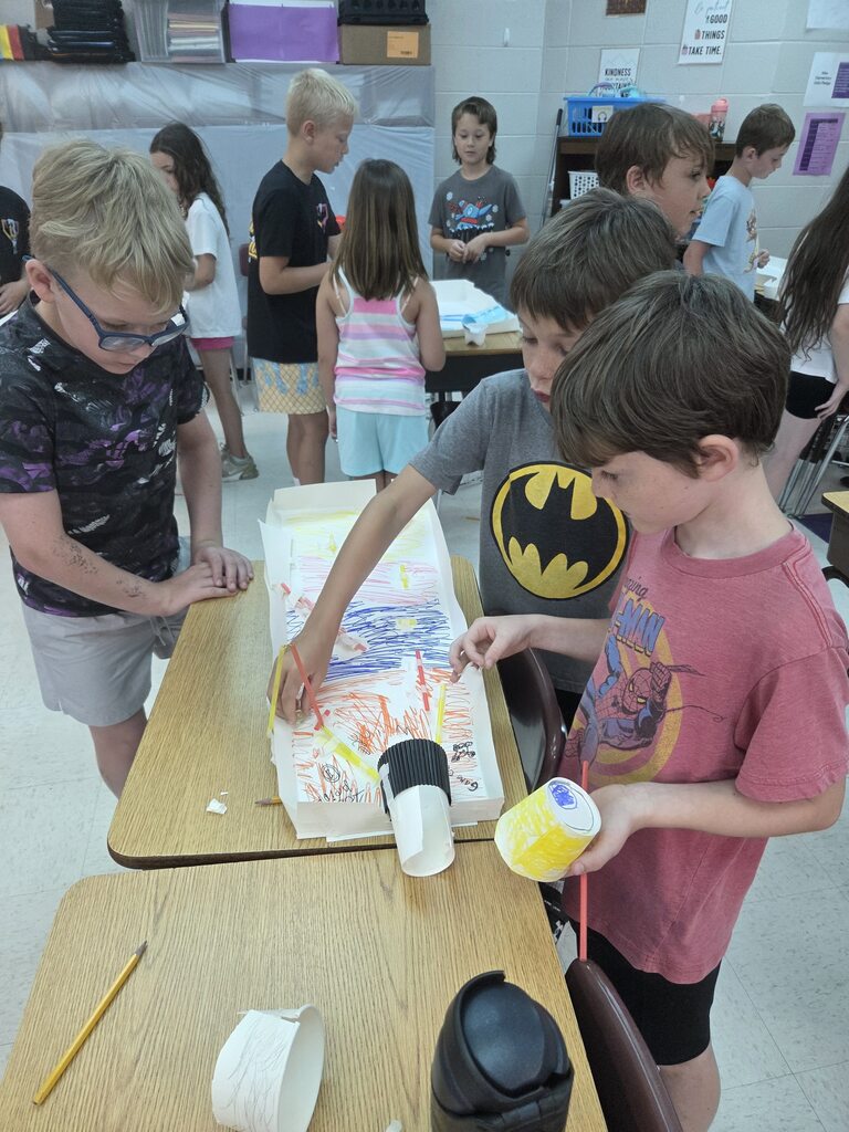 Students collaborate on a colorful homemade marble run, testing and adjusting the course during a STEM activity.
