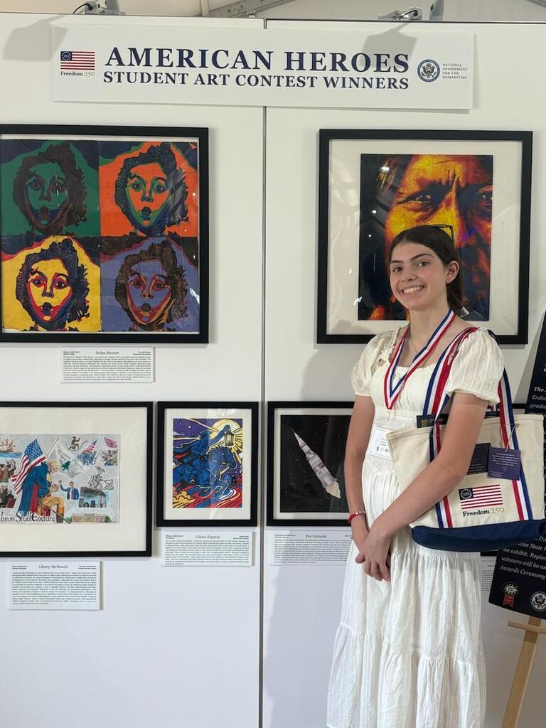 Student poses beside her winning artwork at the American Heroes Student Art Contest winners exhibition.
