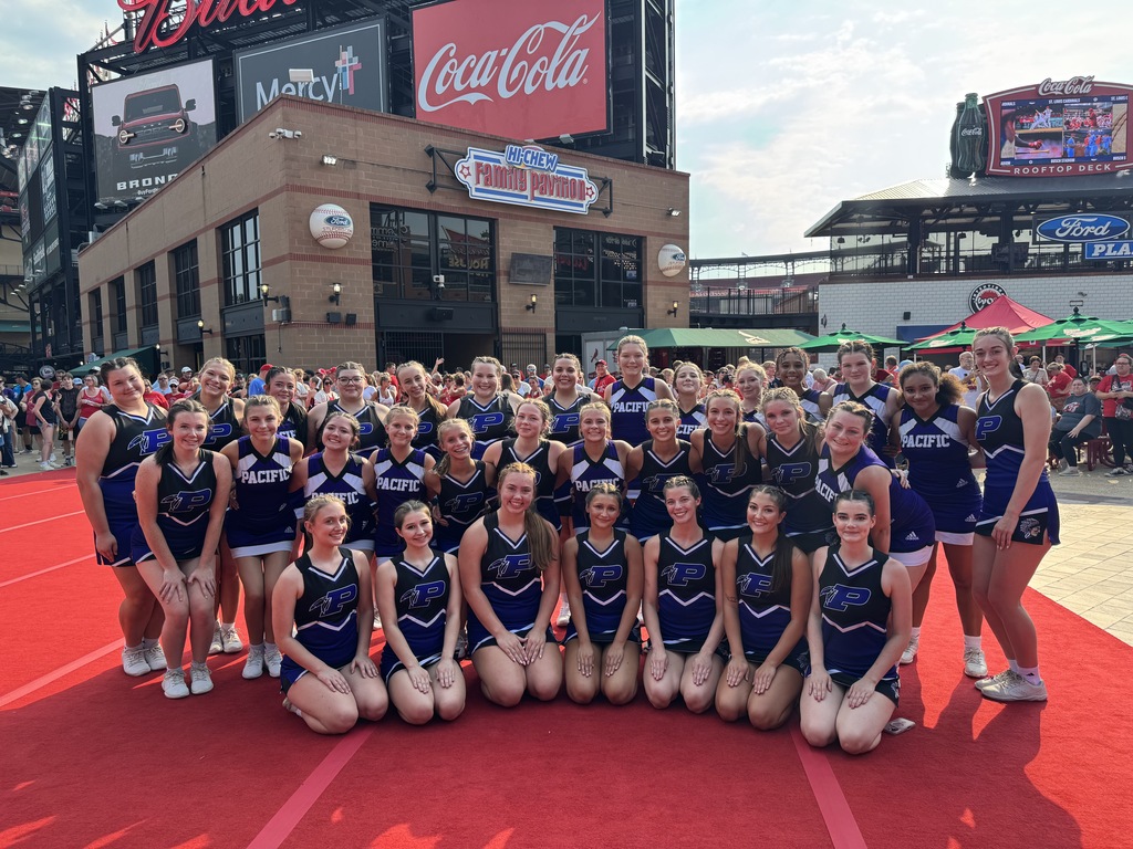 Group cheerleading photo on a red carpet outdoors.