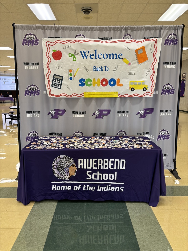 A colorful โWelcome Back to Schoolโ display hangs above a Riverbend School table covered with stickers.