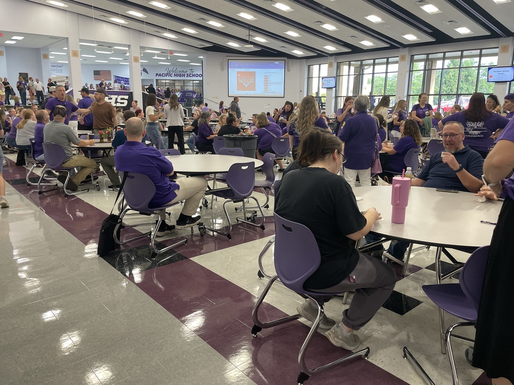 School staff gather and socialize around cafeteria tables.
