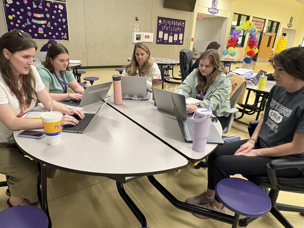 Five teachers collaborating at a cafeteria table.