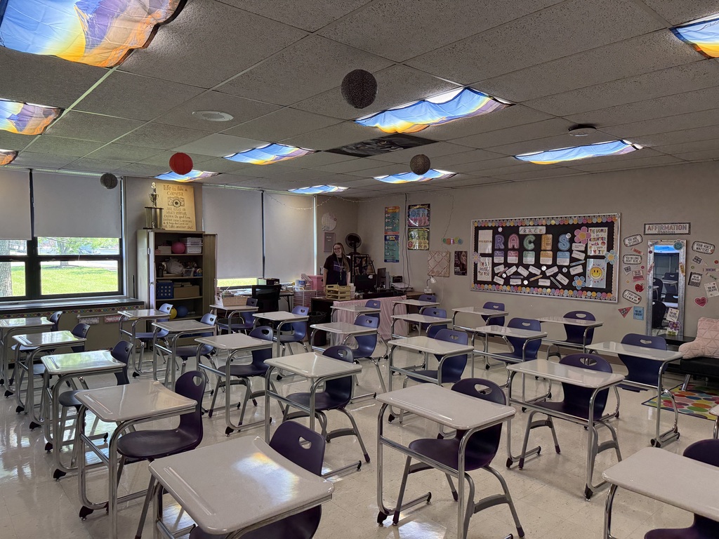 A teacher standing in an empty school classroom.