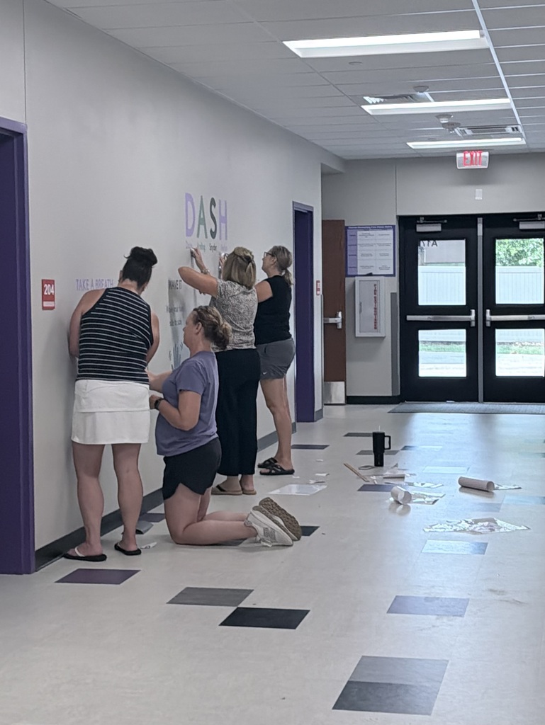 Four adults decorating a school hallway.