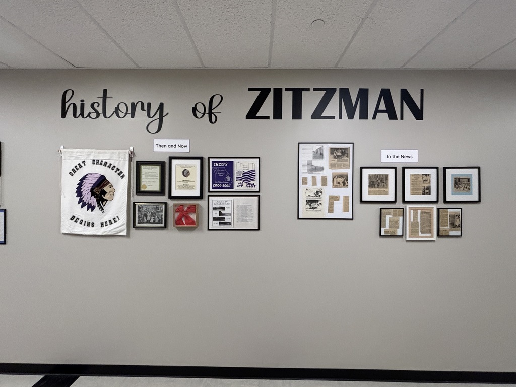 “History of Zitzman” wall display featuring memorabilia, newspaper clippings, awards, and sections labeled “Then and Now” and “In the News.”