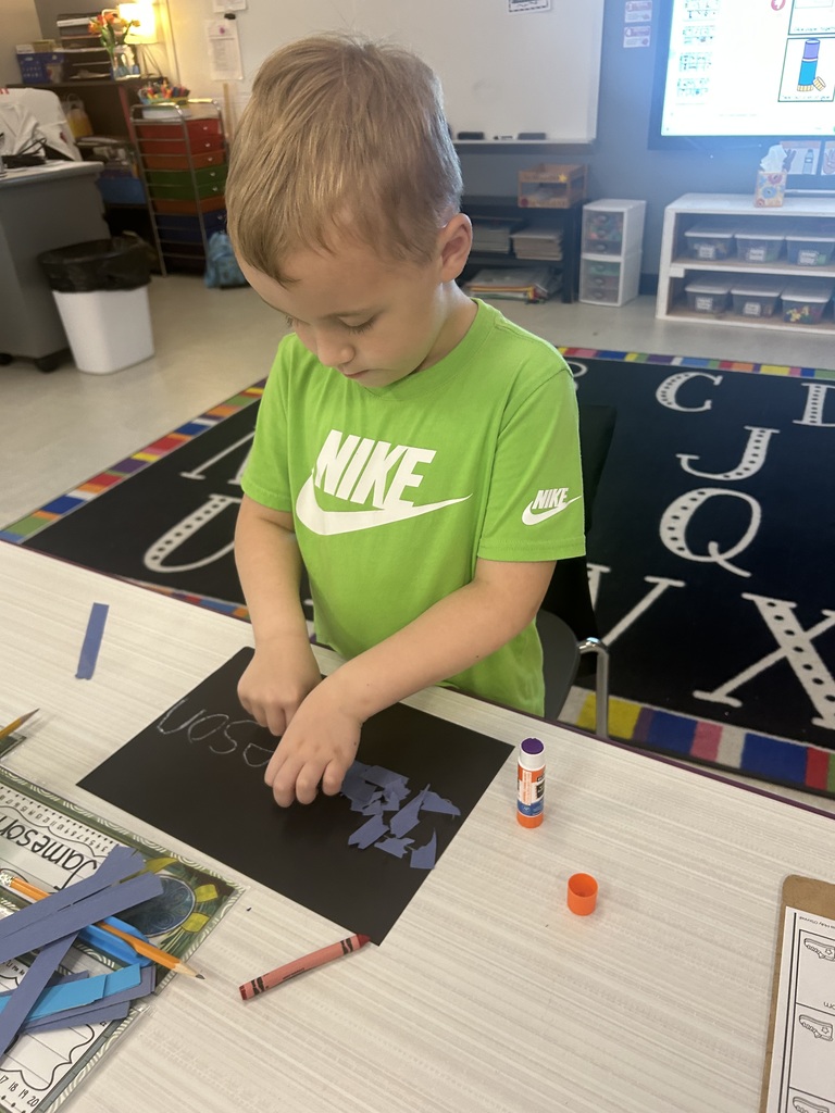 A young student using a glue stick to make a craft.