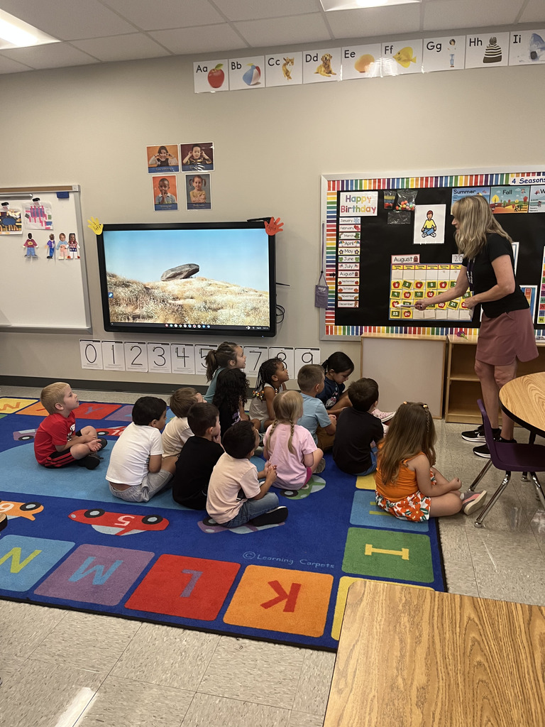 A teacher talking to a group of young students in a school classroom.