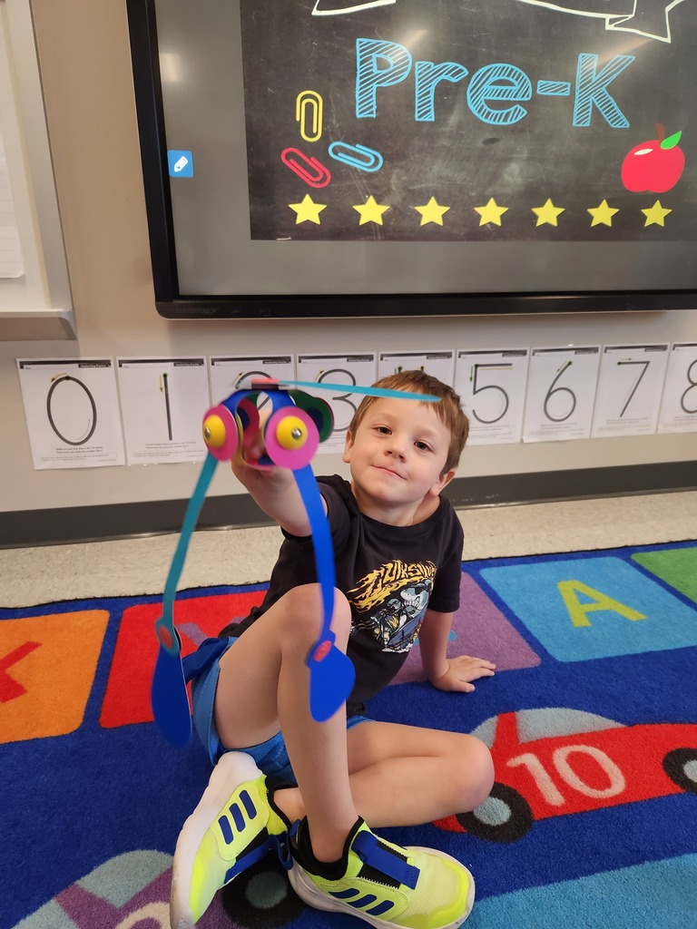 A young student showing a toy in a school classroom.