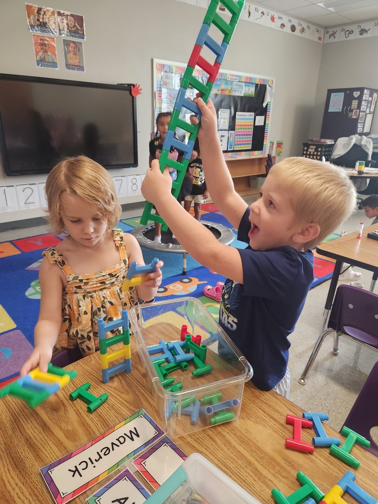 Two students building with a playing blocks in a school classroom.