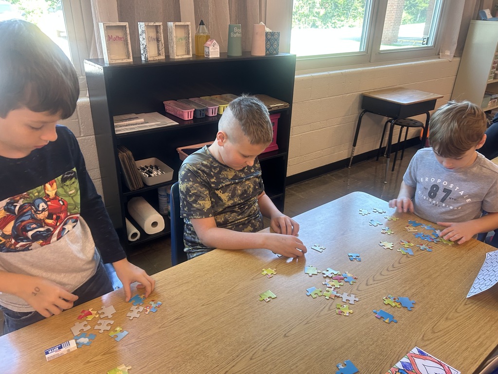 Three young students working a puzzle together.